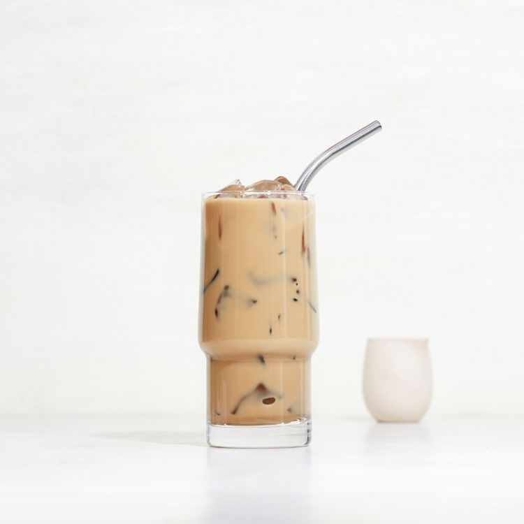 a glass of iced creamy cold brew with a straw