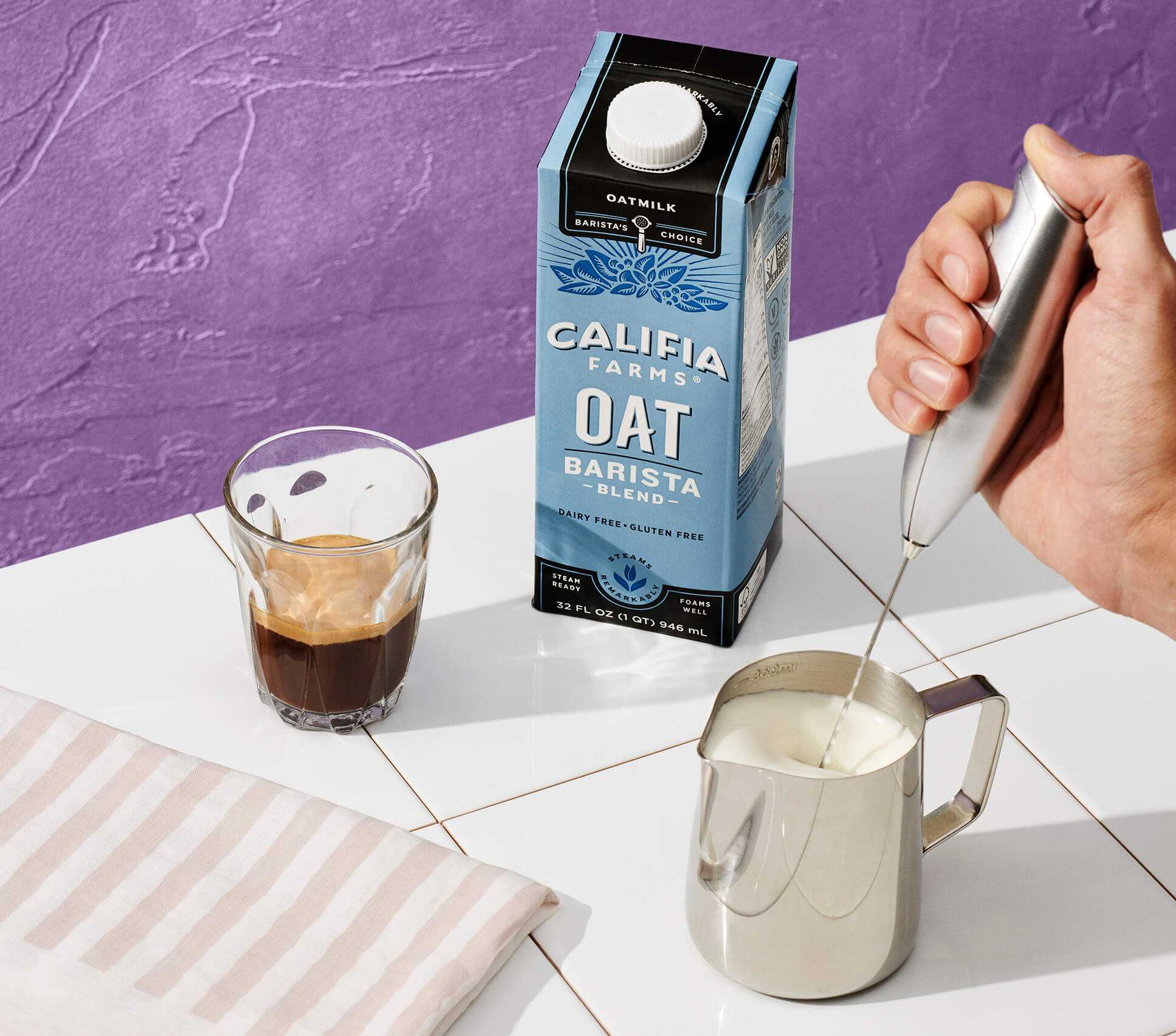 a close-up of oat milk being frothed manually with Califia Barista Blend in the background