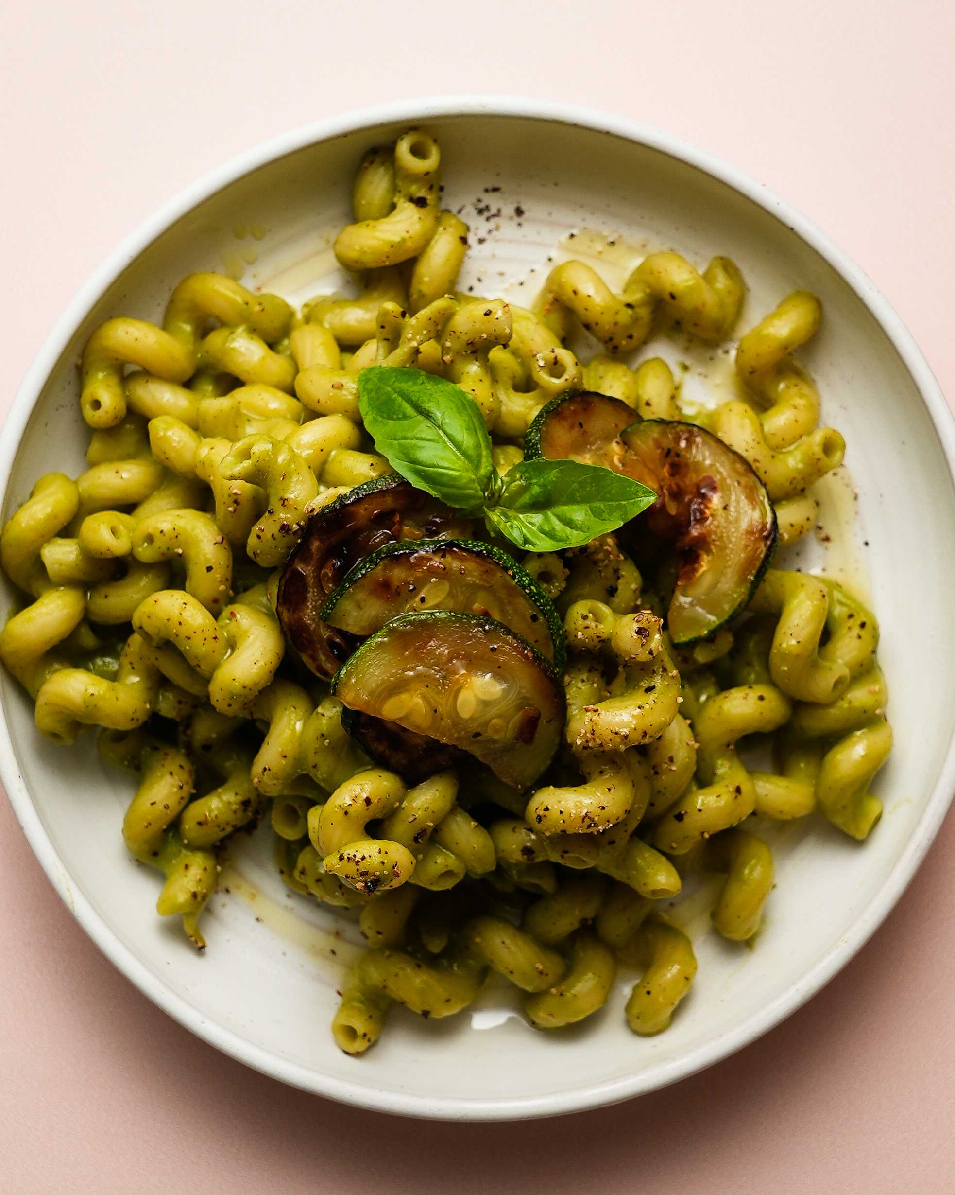 A bowl of zucchini pasta sits in the center of the image.